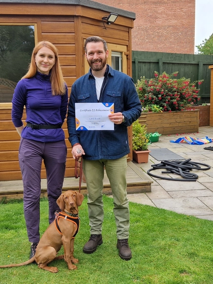 Katya with a proud client and their vizsla holding a training certificate