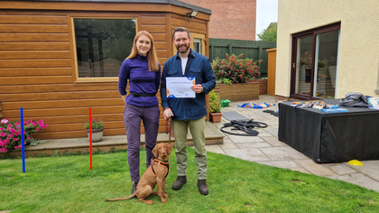 Katya with a proud client and their vizsla holding a training certificate